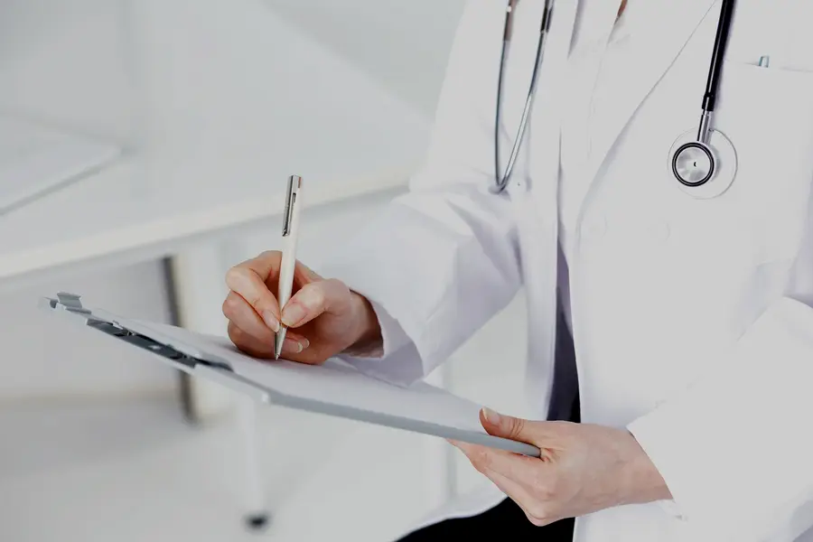 Profesional médica anotando en una historia clínica